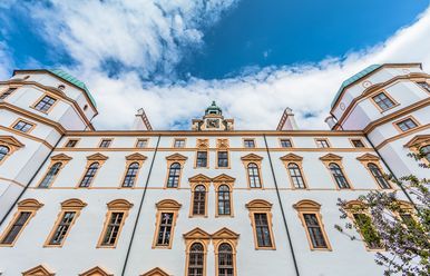 Detailaufnahme der Fassade des Residenzschlosses in Celle mit kunstvoll verzierten Fenstern und Türmen unter einem blauen Himmel mit Wolken.