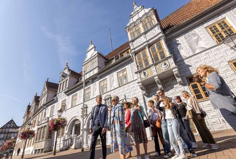 Eine Gruppe von Menschen nimmt an einer Stadtführung in der historischen Altstadt von Celle teil. Der Guide erklärt die Sehenswürdigkeiten und Geschichte der Stadt.