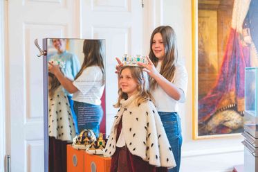 Zwei Kinder verkleiden sich als König und Königin bei einer familienfreundlichen Schlossführung im Celler Schloss.