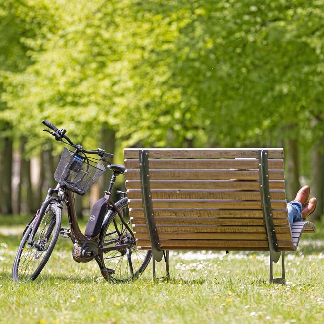 Radfahrer sitzt auf einer Bank im französischen Garten im Frühling.